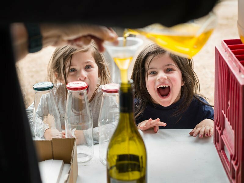 Children smiling at olive oil being poured at Olives to Oil